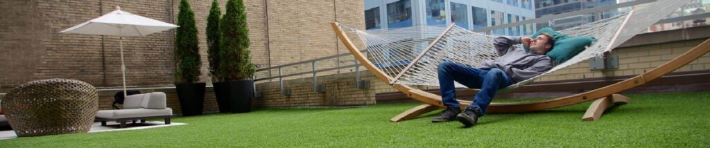 Man relaxing on hammock on artificial grass rooftop