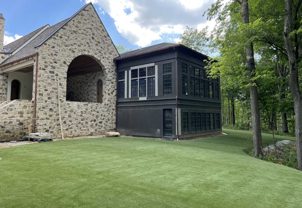 White and black house with artificial grass lawn